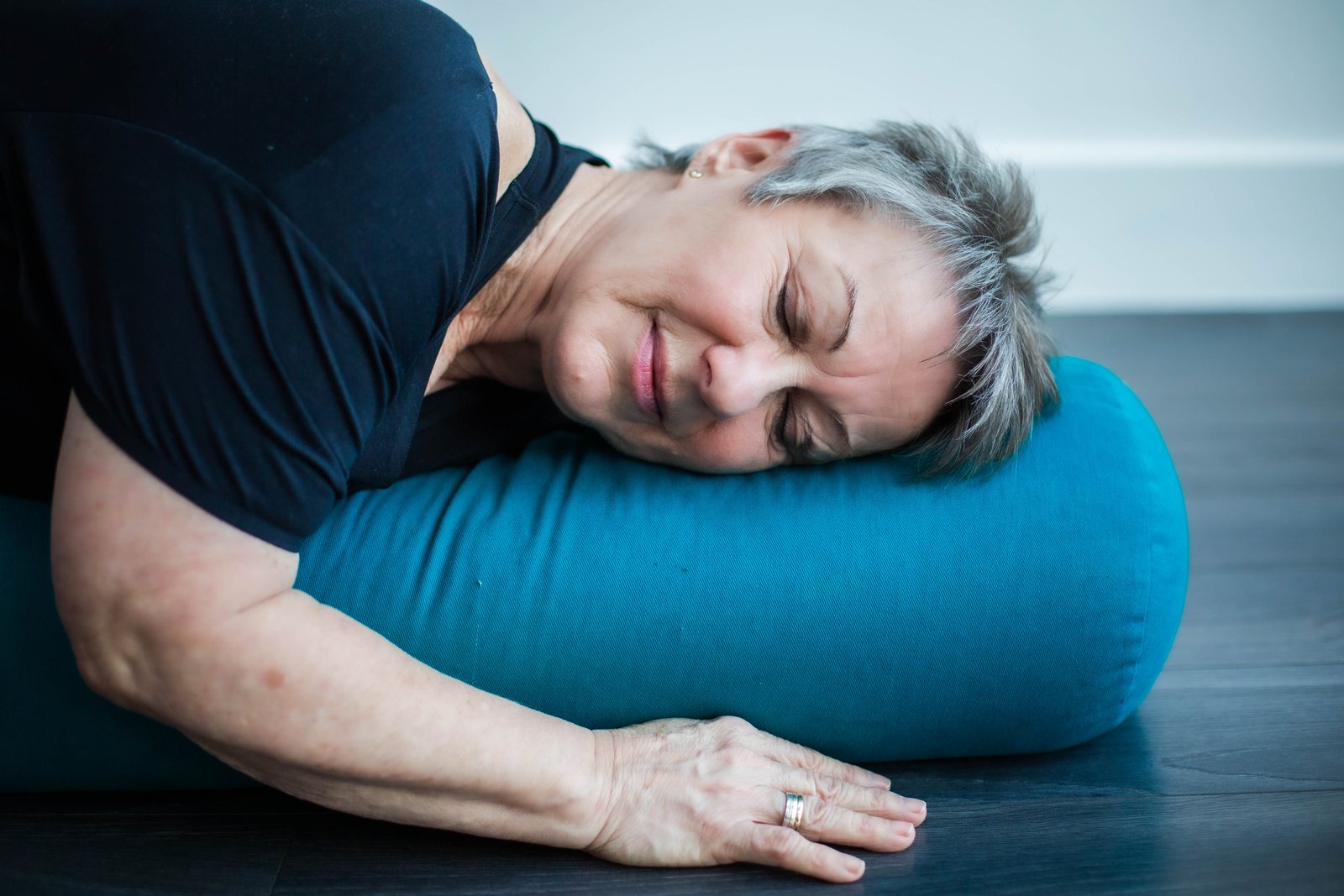 A student resting comfortably on a yoga bolster